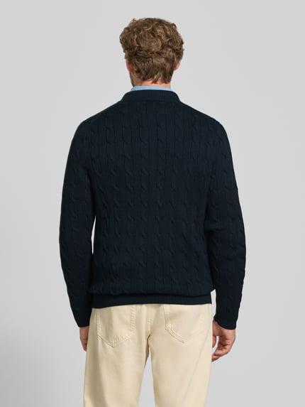 Männermodel trägt Regular Fit Strickjacke aus reiner Baumwolle von Polo Ralph Lauren in Dunkelblau mit Zopfmuster, Ganzkörperansicht Rückansicht. Kontext: Herren Poloshirt von Polo Ralph Lauren.