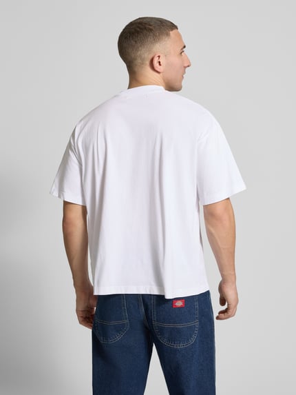 Männermodel trägt Regular Fit T-Shirt mit Logo-Detail von ANOTHER COTTON LAB, reine Baumwolle, weiß, glatte Textur, Rückenansicht, Ganzkörperansicht Rückansicht.