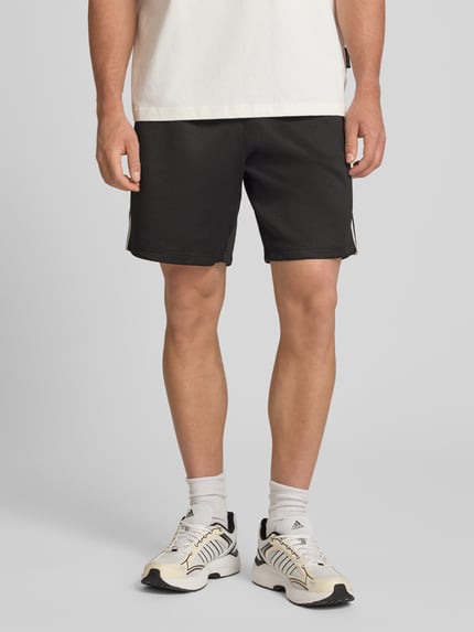 Männermodel trägt Regular Fit Sweatshorts mit elastischem Bund Modell 'RIBER' von Only & Sons, Optik: Unifarben, Kontraststreifen, Eingrifftaschen, Ganzkörperansicht von vorne