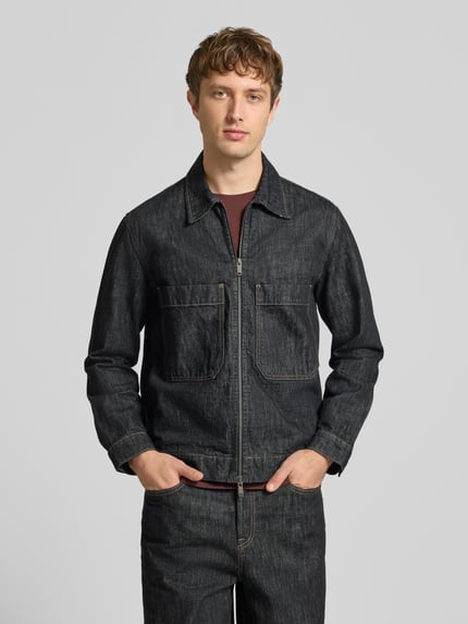 Männermodel trägt Jeansjacke mit Zweiwege Reißverschluss von ONLY in dunkelblauem Denim mit Struktur und Label-Details, Ganzkörperansicht von vorne.