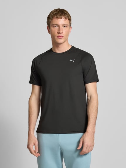 Męski model nosi T-shirt mit Label-Print od PUMA PERFORMANCE, mieszanka materiałów z dodatkiem streczu, krój regular fit, prążkowany okrągły dekolt, nadruk z logo, długość tyłu w rozmiarze M: 71 cm, widok całej sylwetki od przodu.