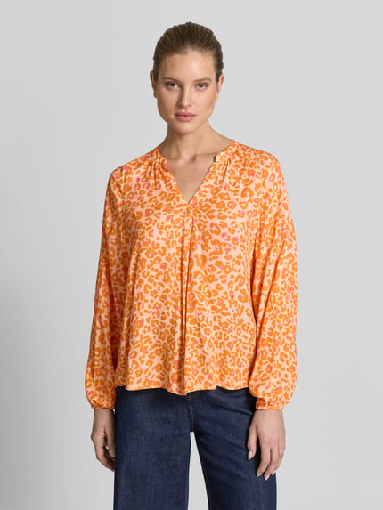 Frauenmodel trägt Damenbluse im Allover-Look mit V-Ausschnitt von Emily Van den Bergh, reine Viskose, orange gemustert, Ganzkörperansicht von vorne