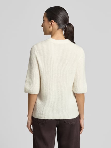 Frauenmodel trägt Strickjacke mit Woll-Anteil Modell 'Jinie Hope' von MSCH Copenhagen in Creme, Struktur glatt, gerader Schnitt, Rückansicht Ganzkörperansicht.