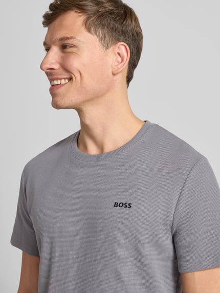 Männermodel trägt Regular Fit T-Shirt aus Baumwoll-Mix von BOSS, Optik: Unifarben, Waffel-Struktur, Rundhals, Kurzarm, Nahaufnahme Oberkörper.