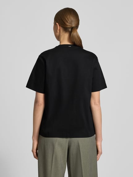 Modelka nosi czarny Relaxed Fit T-Shirt aus reiner Baumwolle Modell 'EHARPA' od BOSS, unifarbny, okrągły dekolt, krótkie rękawy, label stitching, bawełna, zdjęcie całej sylwetki od tyłu.