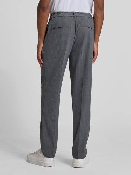 Männermodel trägt Straight Fit Stoffhose mit Bügelfalten Modell 'Marc' von Casual Friday, Elastischer-Material-Mix mit Viskose-Anteil, Ganzkörperansicht Rückansicht.