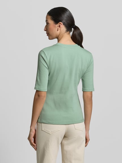 Frauenmodel trägt Slim Fit T-Shirt im Halbarm-Design von Christian Berg Woman in zartem Grün, elastischer Baumwoll-Mix, Rückansicht, Ganzkörperansicht.