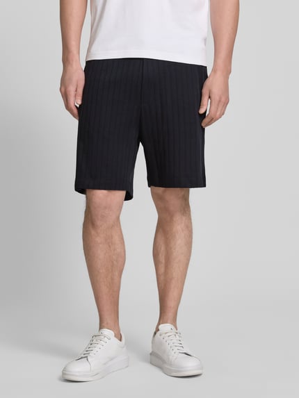 Męski model nosi Regular Fit Shorts mit Tunnelzug Modell 'JUANITO' od JOOP! Collection, czarny, bawełna, krój regular fit, szerokość w rozmiarze M: 43 cm, długość wewnętrzna nogawki: 17 cm, widok całej sylwetki z przodu.