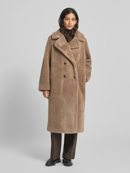 Vrouwenmodel draagt Mantel uit teddybont van Smith and Soul in los model met reverskraag en knoopsluiting, kleur lichtbruin, Ganzkörperansicht van voren. Ruglengte maat S 115 cm, schouderbreedte 44 cm, borstwijdte 62 cm, mouwlengte 62 cm.