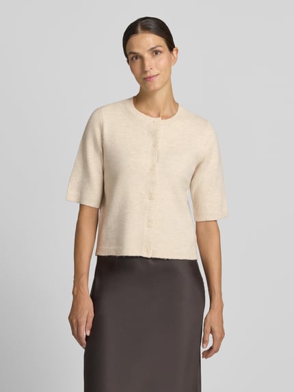Frauenmodel trägt Regular Fit Cardigan in Strick-Optik Modell 'Iga' von VILA, beige Farbe, 1/2-Arm, Knopfleiste, Ganzkörperansicht von vorne.
