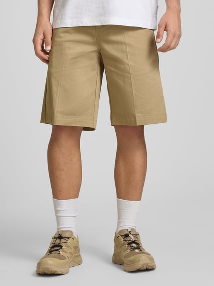 Männermodel trägt Bermudas mit französischen Eingrifftaschen von Dickies, Reine Baumwolle, Straight Fit, Knopf-Reißverschluss, Ganzkörperansicht von vorne.