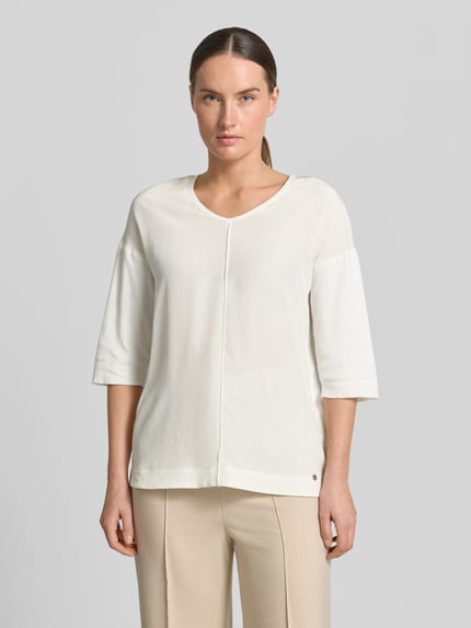 Frauenmodel trägt T-Shirt mit Ärmelaufschlag und Rundhalsausschnitt von Marc Cain, Baumwoll-Mix mit Stretch-Anteil, Straight Fit, Label-Detail, cremefarben, Rückenlänge bei Größe 36: 62 cm, Ganzkörperansicht von vorne.