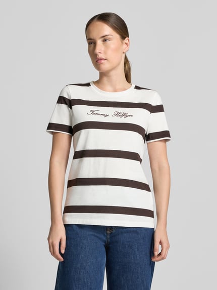 Vrouwenmodel draagt Regular Fit T-shirt uit puur katoen van Tommy Hilfiger, wit met brede bruine strepen, Ganzkörperaanzicht van voren.