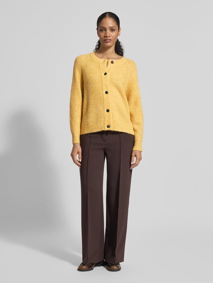 Frauenmodel trägt Regular Fit Strickjacke aus Woll-Mix mit Alpaka-Anteil Modell 'LULU' von Selected Femme, Optik: Unifarben, Rippstrick, einreihige Knopfleiste, Crew Neck, Langarm, Raglanärmel, Ärmel- und Rumpfabschluss gerippt, Farbe Gelb, Materialverarbeitung: Woll-Mix; Ganzkörperansicht von vorne.