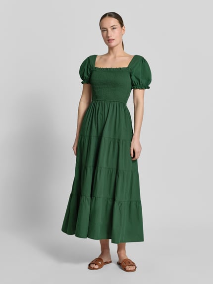 Frauenmodel trägt Maxikleid mit Smok-Details und Karree-Ausschnitt von Apricot in Grün, Reine Baumwolle, Rüschenärmel, taillierter Schnitt, Ganzkörperansicht von vorne. Rückenlänge bei Größe S: 116 cm, Brustweite: 32 cm, Ärmellänge: 21 cm.