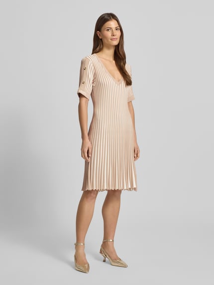 Frauenmodel trägt Minikleid mit gerippten Abschlüssen von LIU JO SPORT aus Viskose-Mix in Beige, tailliert, V-Ausschnitt, Label-Print, Ganzkörperansicht von vorne.