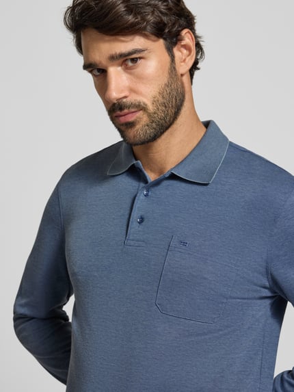 Männermodel trägt Regular Fit Poloshirt mit Baumwoll-Anteil von Christian Berg Men in Blau, glatte Textur, Brusttasche, Nahaufnahme Oberkörper.