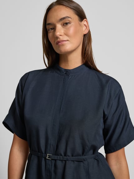Vrouwenmodel draagt een donkerblauwe Tailliertes Freizeitkleid aus Lyocell-Leinen-Mix Modell 'DALINIA' van BOSS met decoratieve naden, uni kleur, getailleerde fit, mini lengte, opstaande kraag, korte mouwen, afneembare riem, ceintuurlussen, steekzakken en verdekte knoopsluiting, materiaal lyocell-linnenmix. Close-up bovenlichaam vooraanzicht.
