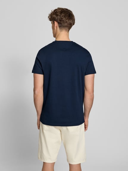 Männermodel trägt Regular Fit T-Shirt aus reiner Baumwolle von Tommy Jeans in Optik: Unifarben, Jersey-Struktur, Ganzkörperansicht Rückansicht.