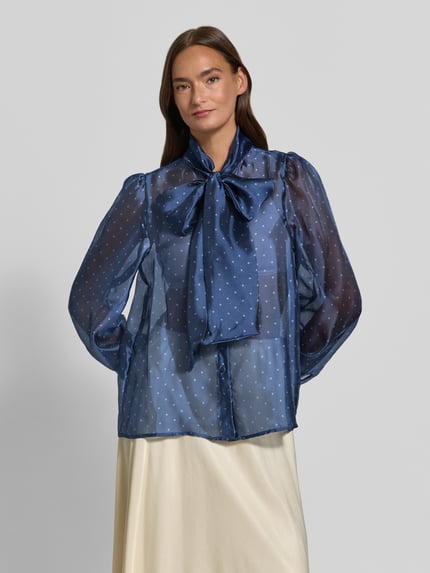 Frauenmodel trägt Schluppenbluse im semitransparenten Design von Rich & Royal, gerade geschnitten, Schluppe, verdeckte Knopfleiste, Rückenlänge 64 cm, Ärmellänge 66 cm, blau mit Punktmuster, Ganzkörperansicht von vorne.