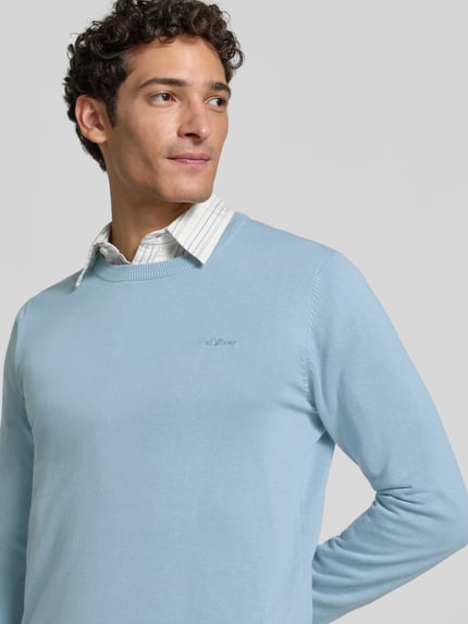 Mężczyzna nosi Regular Fit Pullover aus reiner Baumwolle od s.Oliver RED LABEL w jasnoniebieskim kolorze, gładka tekstura, zbliżenie na górną część ciała.