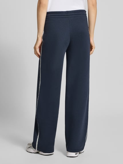 Frauenmodel trägt Wide Fit Sweatpants aus Baumwoll-Mix von REVIEW in Dunkelblau mit Bordüre und elastischem Bund, Ganzkörperansicht Rückansicht.