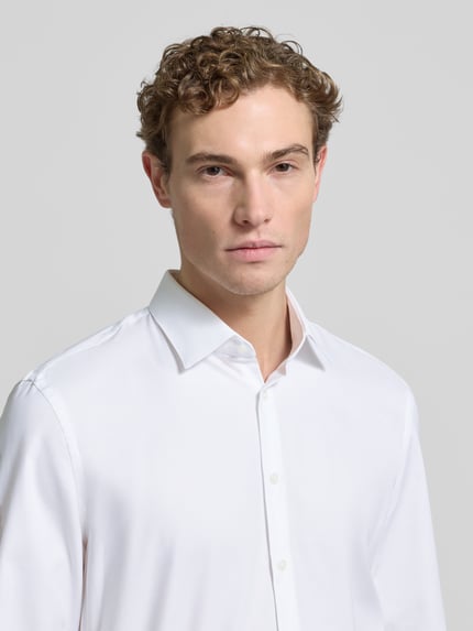 Männermodel trägt Super Slim Fit Businesshemd mit Kentkragen von Jake*s, Optik: Unifarben, Baumwoll-Elasthan-Mix, Nahaufnahme Oberkörper.