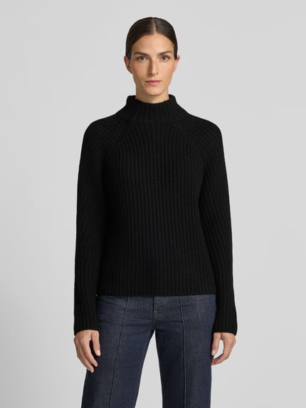 Frauenmodel trägt schwarzen Strickpullover aus Kaschmir-Baumwoll-Mix Modell 'LONA' von 0039 Italy, Struktur mit Stehkragen, Ganzkörperansicht von vorne. Reguläre Passform, sichtbare Stricktextur. Rückenlänge 60 cm, Ärmellänge 78 cm bei Größe 36.