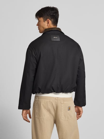Männermodel trägt schwarze Twill Jacke mit Label- und Motiv-Stitching von ANOTHER COTTON LAB, glatte Oberfläche, Ganzkörperansicht Rückansicht.