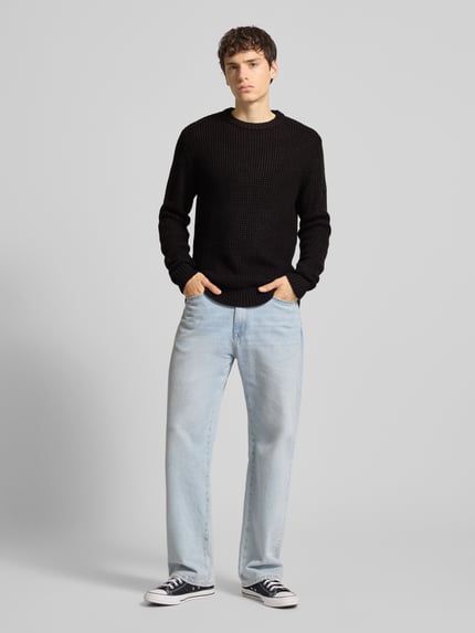 Männermodel trägt Strickpullover mit gerippten Abschlüssen Modell 'LIAM' von JACK & JONES, schwarzer Baumwoll-Mix, Regular-Fit, Ganzkörperansicht von vorne.