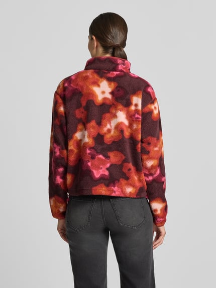Frauenmodel trägt Fleeceshirt mit Stehkragen und Label-Patch Modell 'Helvetia II' von Columbia, bunt gemustert, Polar, Ganzkörperansicht Rückansicht, Długość tyłu w rozmiarze S: 57 cm, szerokość ramion w rozmiarze S: 48 cm, szerokość w rozmiarze S: 54 cm, długość rękawów w rozmiarze S: 59 cm.