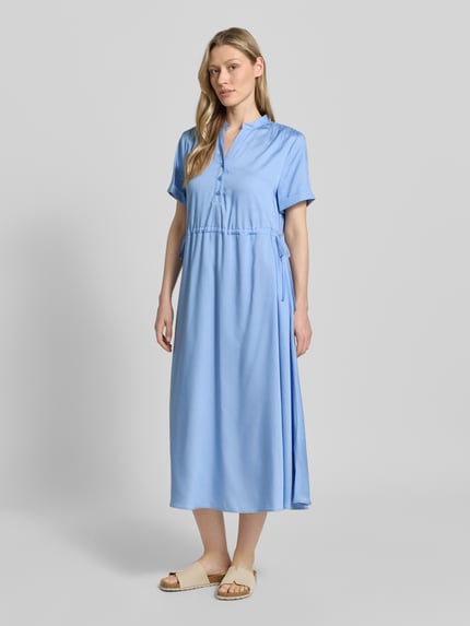 Frauenmodel trägt Midikleid aus Lyocell mit V-Ausschnitt von More & More in Hellblau, A-Linie, Stehkragen, Knopfleiste, Ärmel mit Aufschlag, regulierbares Taillenband, Ganzkörperansicht von vorne. Rückenlänge 123 cm, Brustweite 52 cm, Ärmellänge 21 cm, Größe 36.