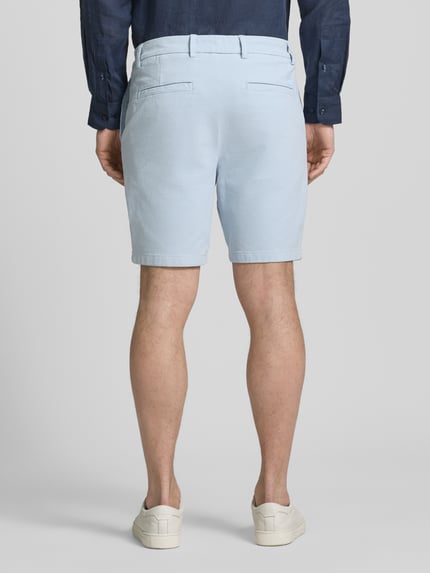 Männermodel trägt Modern Fit Chinoshorts aus Baumwoll-Mix Modell 'KANE1' von BOSS, hellblau, unifarben, Paspeltaschen, Ganzkörperansicht Rückansicht