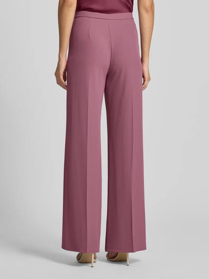 Vrouwenmodel draagt Wide Leg Stoffhose met Knopfverschluss van Rinascimento in roze Materiaalmix met stretch, Ganzkörperansicht Rückansicht, Bandwijdte maat S 40 cm, Binnenbeenlengte maat S 85 cm.