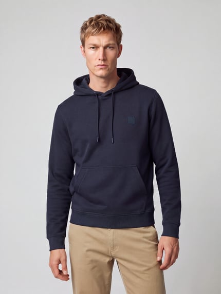 Männermodel trägt Hoodie mit Logo-Patch Modell 'Wetalk' von BOSS Orange in Dunkelblau, Struktur, Kängurutasche, Ganzkörperansicht von vorne.