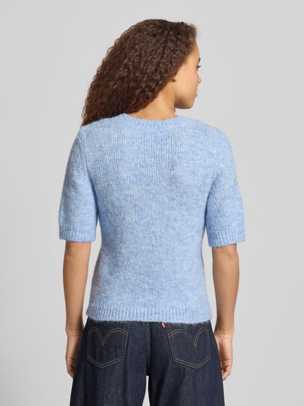Frauenmodel trägt Regular Fit Strickpullover mit Woll-Anteil Modell 'STARLA' von Only in meliertem Hellblau, gerippte Abschlüsse, Ganzkörperansicht Rückansicht.