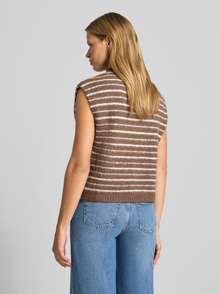 Frauenmodel trägt Regular Fit Weste mit Woll-Anteil Modell 'SIRA' von PIECES in Braun mit weißen Streifen zu blauer Jeans, Ganzkörperansicht Rückansicht. Damen Weste von PIECES.