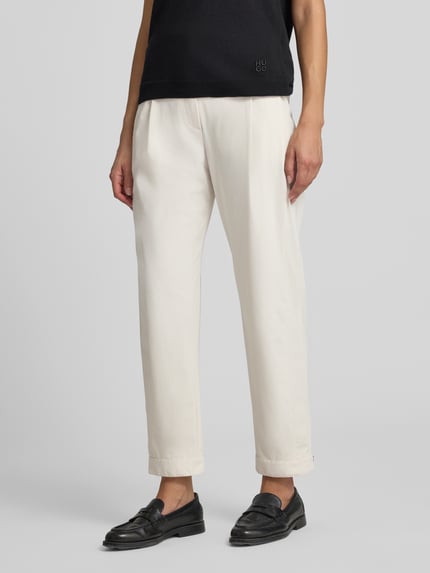 Frauenmodel trägt Bundfaltenhose in Two-Tone-Machart von Marc Cain, helle Farbe, Relaxed Fit, Material-Mix mit Stretch, Nahaufnahme Unterkörper.