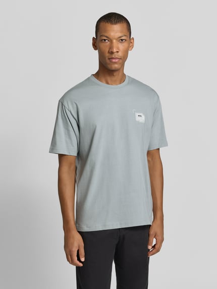 Männermodel trägt Regular Fit T-Shirt aus reiner Baumwolle Modell 'Te_Frame' von BOSS für Herren in Hellgrau, Ganzkörperansicht von vorne, Kontext BOSS Orange.