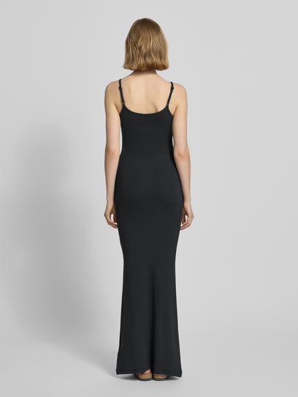 Männermodel trägt czarne Slip Dress mit Feinripp und Spaghettiträgern Modell 'Corin' von LeGer by Lena Gercke, bawełna, krój slim fit, długość maxi, szerokość w rozmiarze 36: 26 cm, długość pleców: 124 cm, widok całej sylwetki z tyłu.