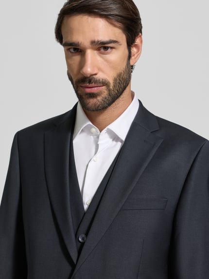 Männermodel trägt Regular Fit 2-Knopf-Sakko mit Pattentaschen von bugatti in Dunkelgrau, Reverskragen, Material-Mix, Nahaufnahme Oberkörper.
