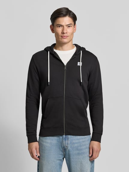 Męski model nosi bluza rozpinana z naszywką z logo i kieszenią kangurka od Scotch & Soda, czarna bawełna, prosty krój, całkowity widok z przodu