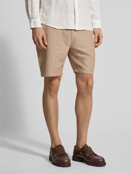 Mannenmodel draagt Shorts aus Baumwoll-Leinen-Mix mit elastischem Bund van Scotch & Soda, regular fit, beige, detailopname benen, context: heren shorts, katoen-linnenmix, elastische tailleband, trekkoord, taillewijdte maat 32: 43 cm, binnenbeenlengte maat 32: 20 cm.