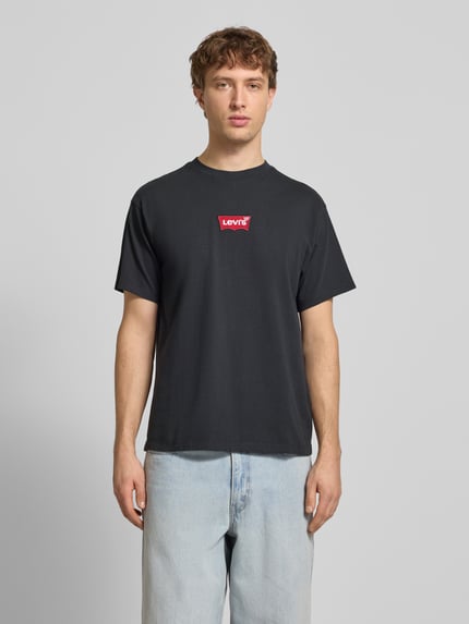 Männermodel draagt T-shirt met labeldetail van Levi's®, puur katoen, regular fit, ronde hals, ruglengte 68 cm bij maat M, Ganzkörperansicht von vorne.