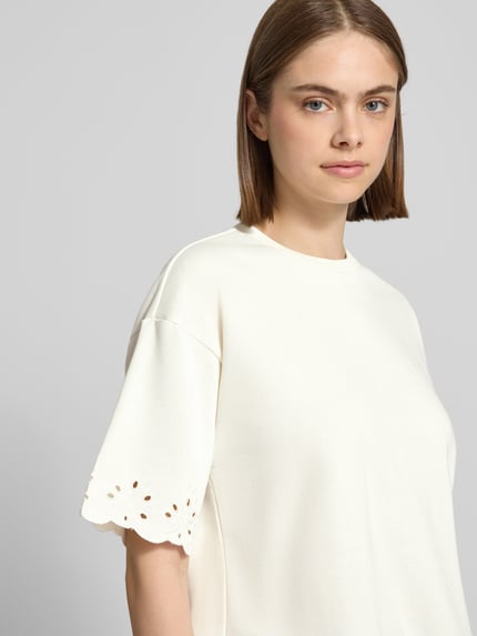 Frauenmodel trägt Boxy Fit T-Shirt aus Baumwoll-Mix Modell 'CHILLI SUMMER' von Pieces, Optik: Unifarben, Regular-Fit, Lochstickdetails, Rundhals, Muschelsaum, Nahaufnahme Oberkörper.