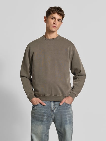 Męski model nosi Sweatshirt mit Label-Stitching von Forét, kolor khaki, bawełna ekologiczna, prosty krój, okrągły dekolt, prążkowane wykończenia, długość tyłu w rozmiarze M: 68 cm, widok całej sylwetki z przodu