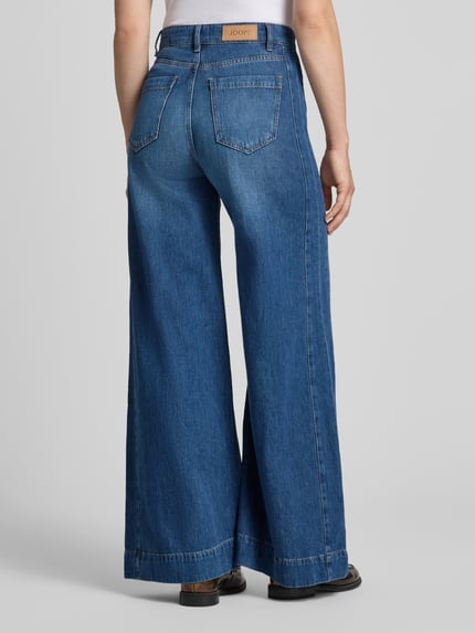 Frauenmodel trägt Wide Leg Jeans mit Label-Detail Modell 'Eila' von JOOP!, reine Baumwolle, blaue Waschung, Ganzkörperansicht Rückansicht.