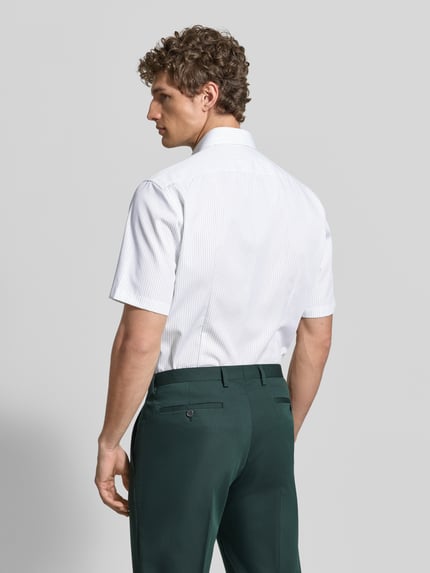 Männermodel trägt wit modern fit zakelijk Modern Fit Business-Hemd met borstzak van OLYMP van puur katoen met kentkraag, knoopsluiting, gestikt logo, afgeronde zoom, ruglengte maat 40: 79 cm, schouderbreedte: 45 cm, mouwlengte: 28 cm, geheel witte kleur, gladde textuur. Ganzkörperansicht Rückansicht.
