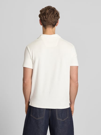 Männermodel trägt Slim Fit Poloshirt aus Frottee von Superdry in Weiß, Reine Baumwolle, Kurzärmelig, Rückenlänge 67 cm, Ganzkörperansicht Rückansicht.