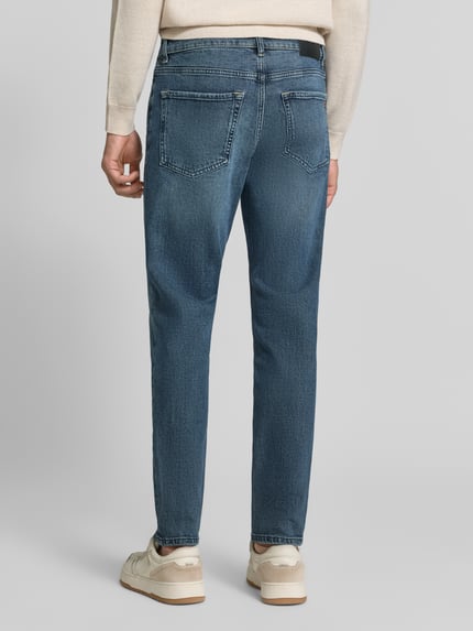 Männermodel trägt Regular Fit Jeans mit Used Waschung Modell 'ONYX SMU' von BOSS Orange, Medium Wash Denim, 5-Pocket, Ganzkörperansicht Rückansicht.